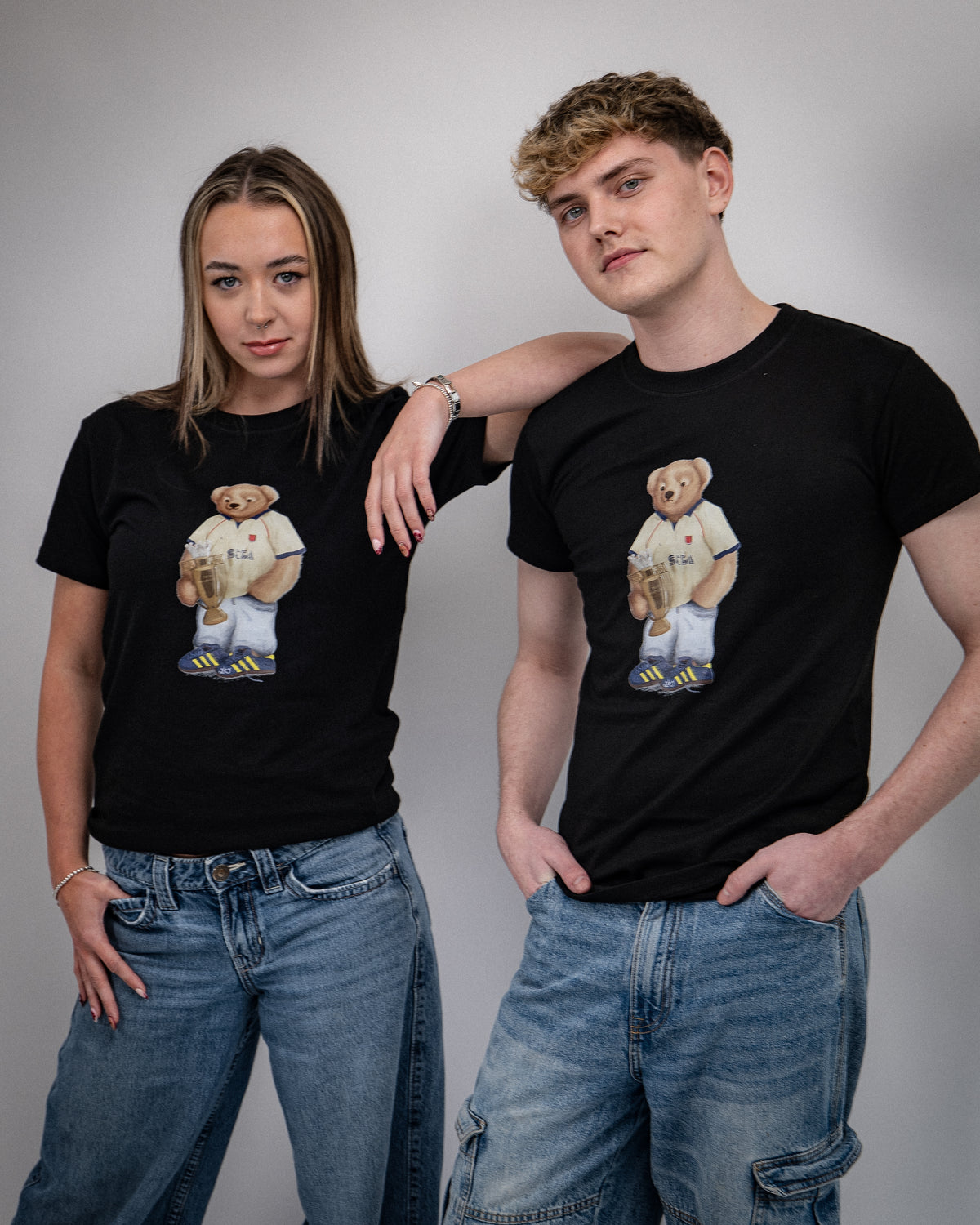 Two people wearing black t-shirts with a bear graphic design on a gray background