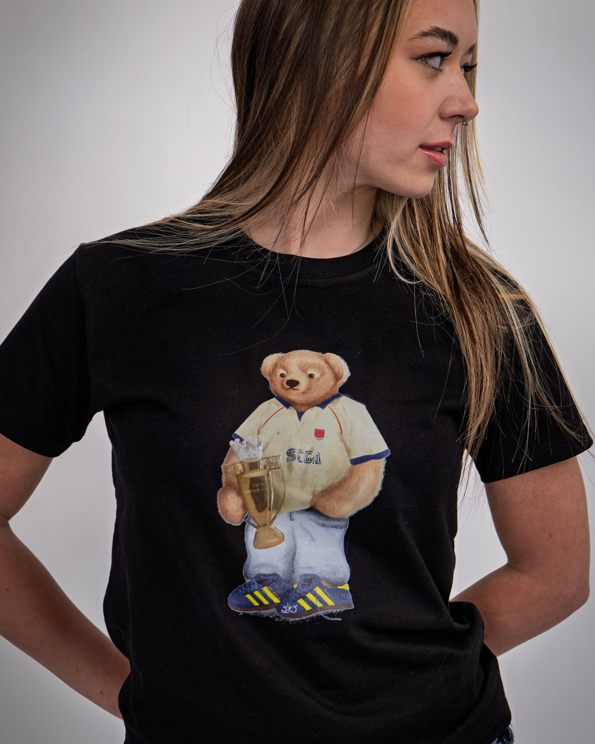 Person wearing a black t-shirt with a bear graphic holding a trophy on a plain background
