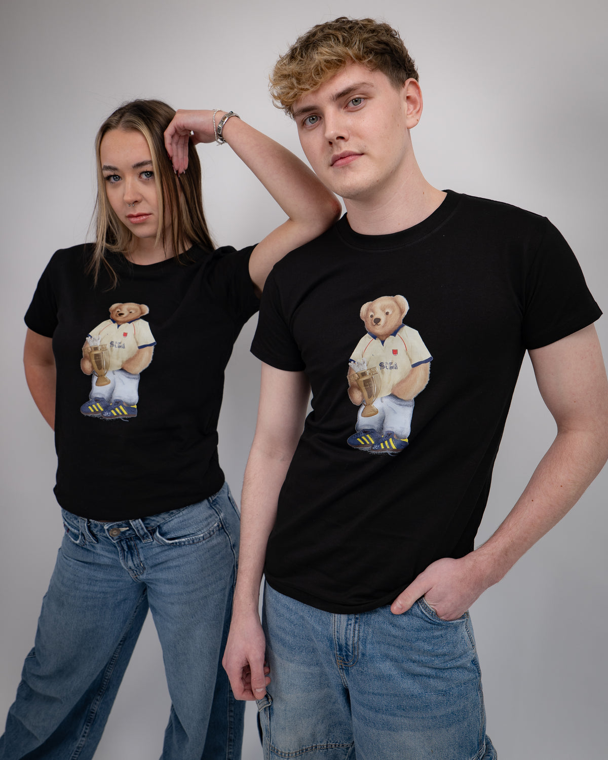 Two people wearing black t-shirts with a bear graphic design on a plain background