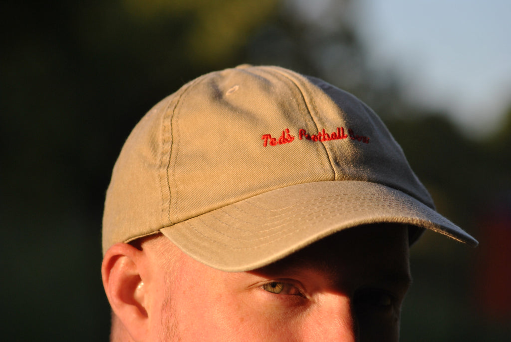 Man wearing a beige cap embroidered with red text 'teds football box'