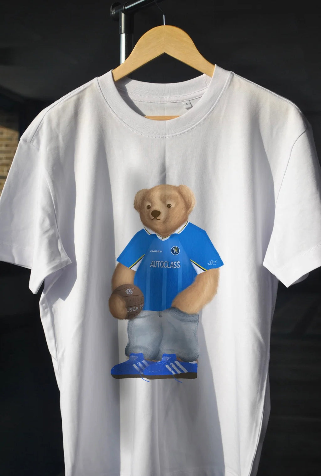 White t-shirt with a bear wearing a blue jersey 