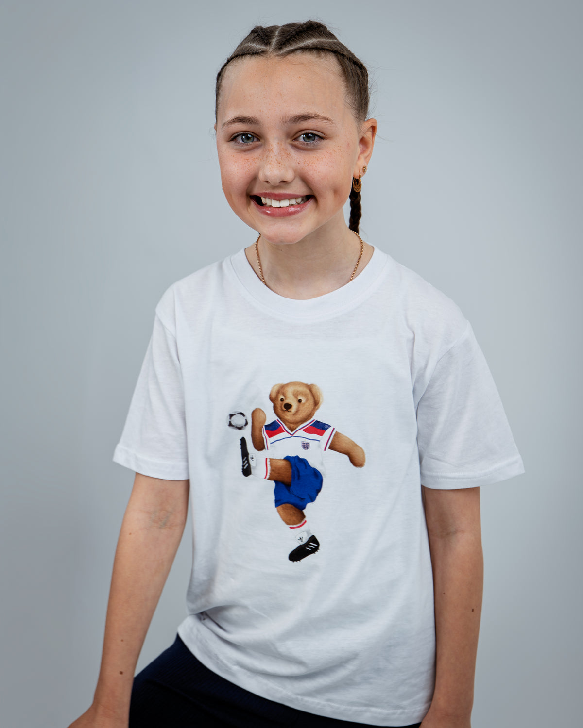Child wearing a white t-shirt with a bear graphic on a gray background
