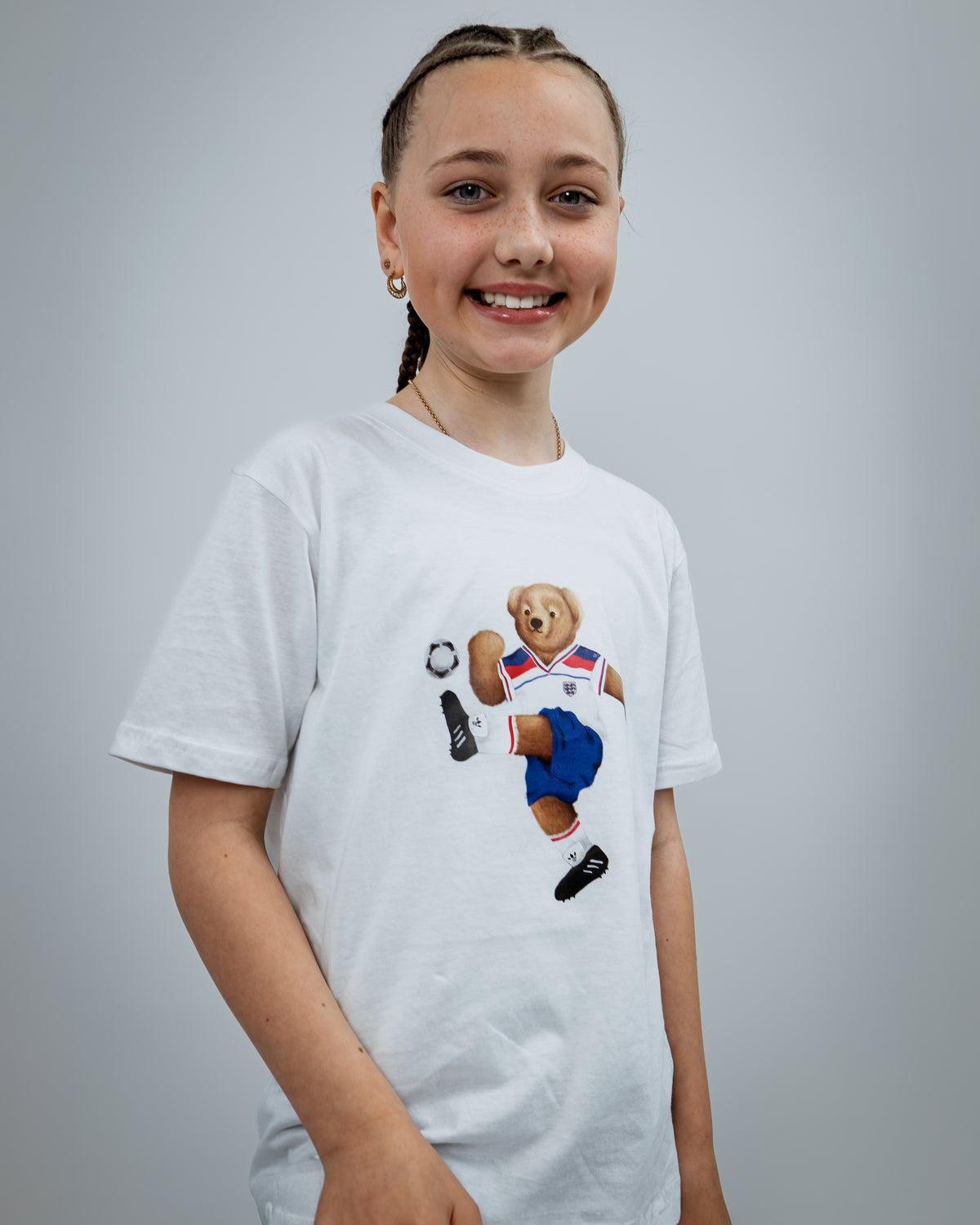 Young girl wearing a white t-shirt with a bear graphic on a gray background