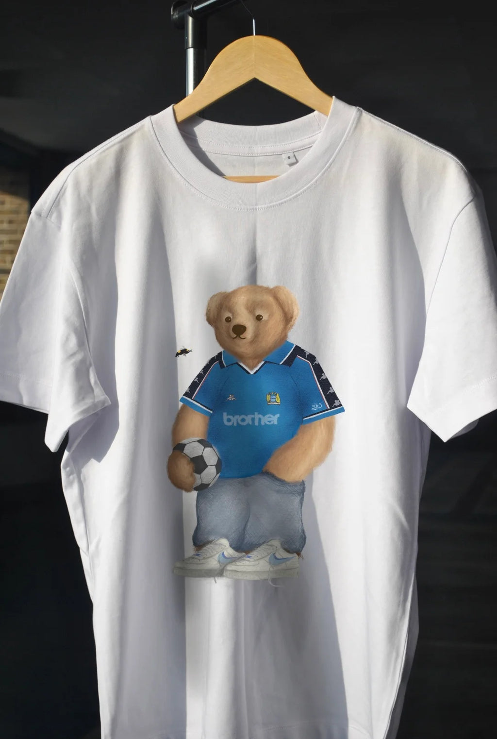 White t-shirt with a bear holding a soccer ball 