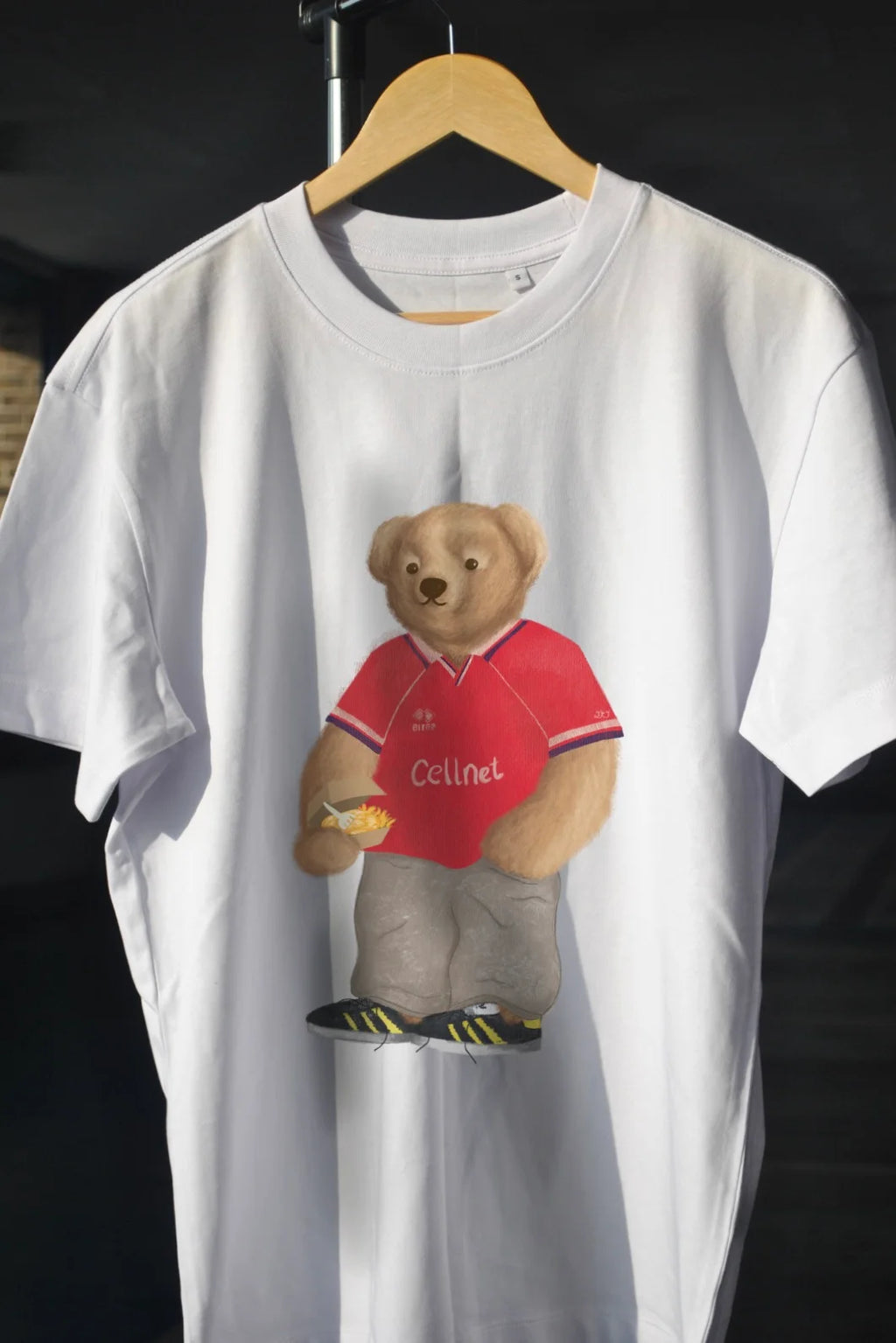 White t-shirt with a bear graphic wearing a red shirt on a hanger.