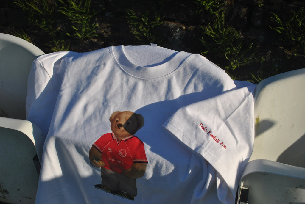 White t-shirt with a bear graphic and text on a chair outdoors