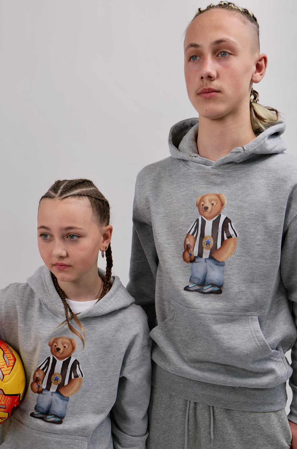 Two people wearing matching gray hoodies with bear graphics on a white background