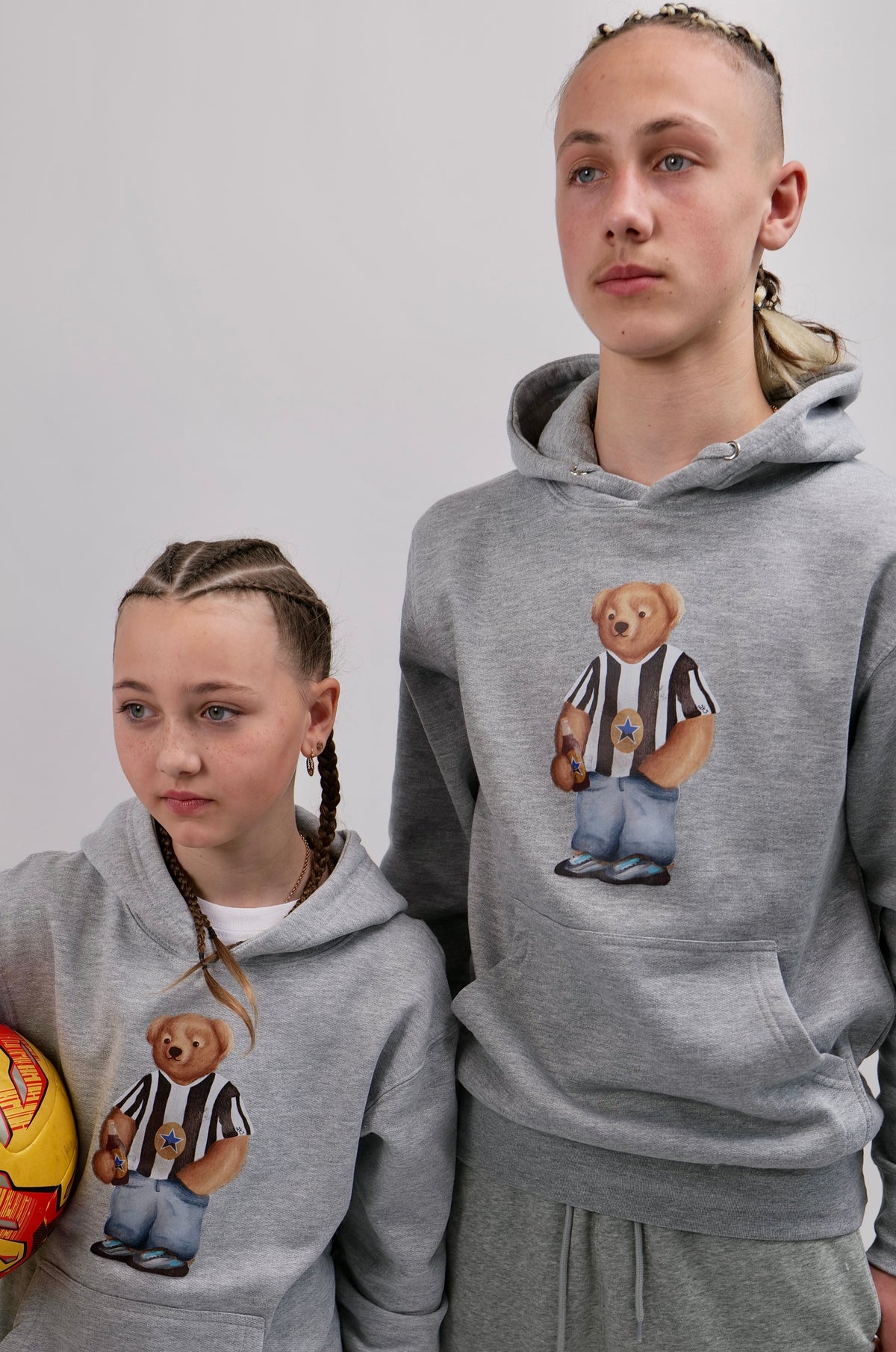 Two people wearing matching gray hoodies with bear graphics on a white background