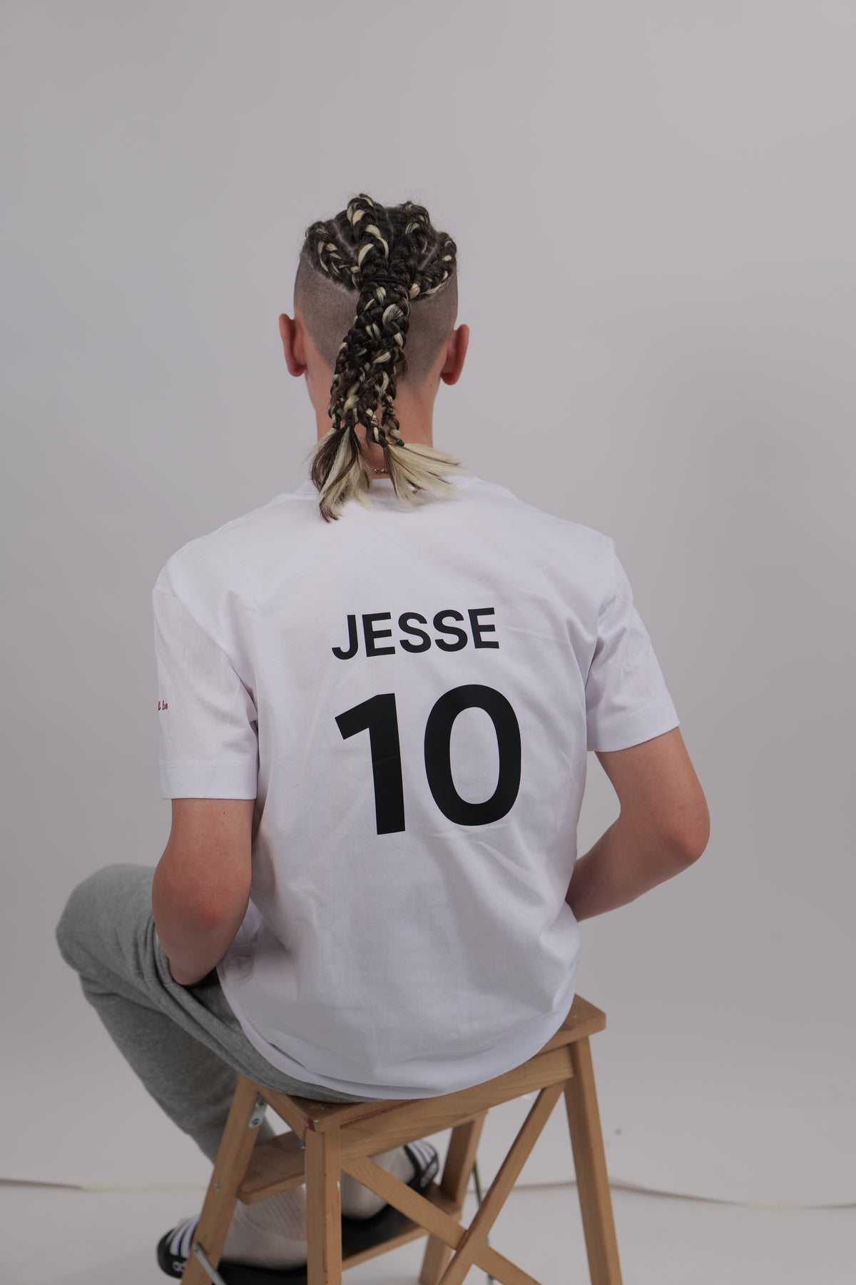 Person wearing a white shirt with 'JESSE' and number '10' on a light gray background