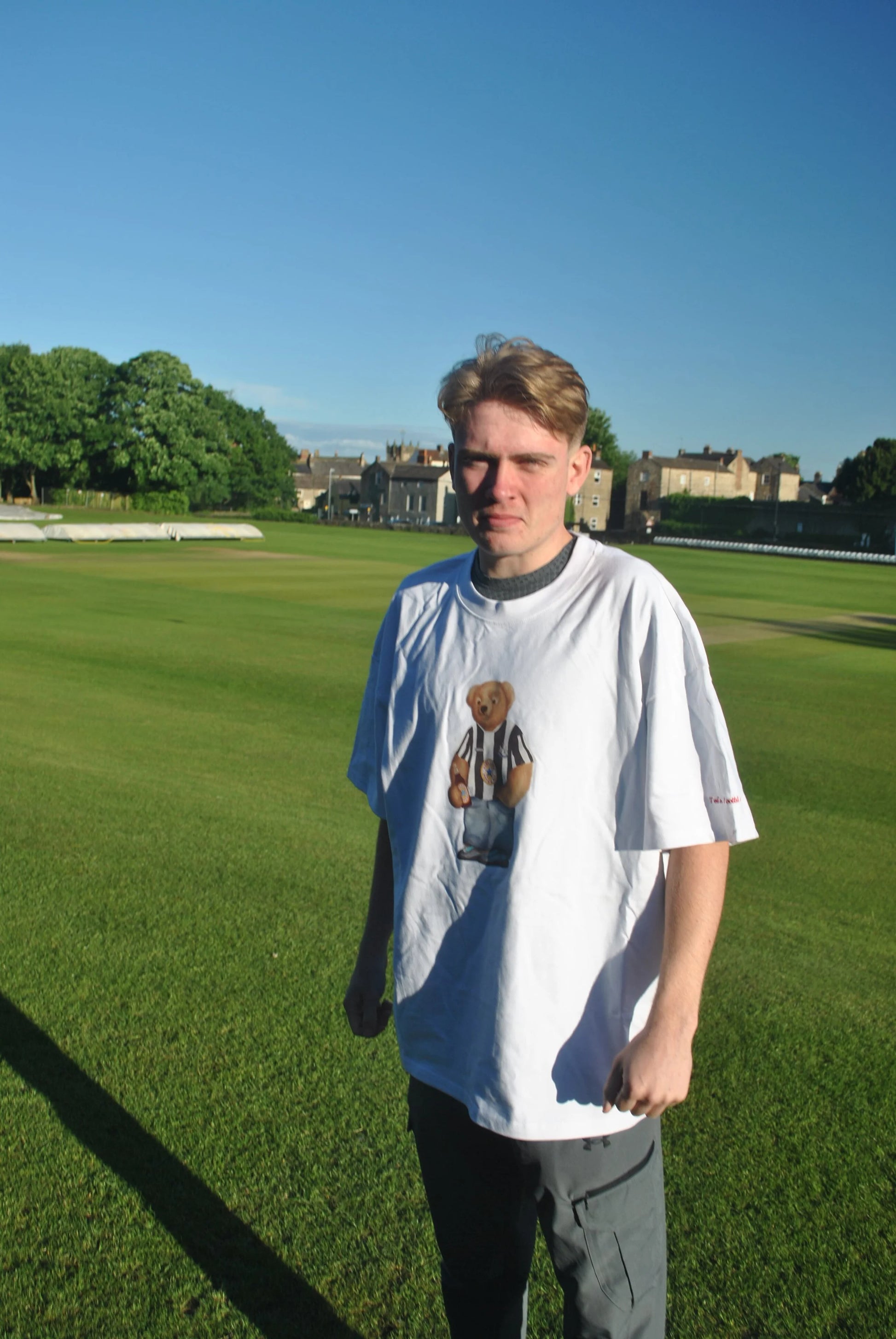 Person wearing a white t-shirt with a graphic design on a grassy field