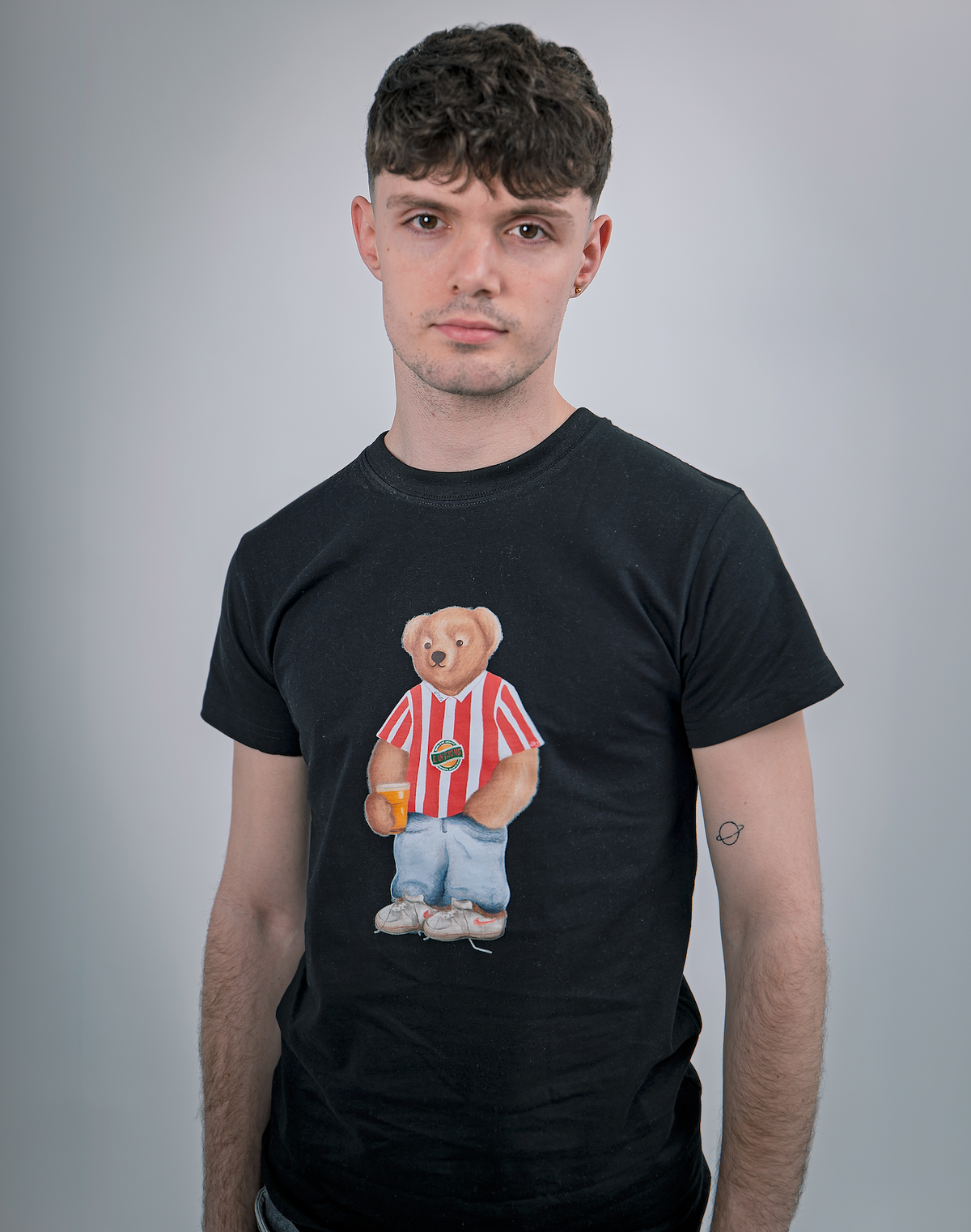 Man wearing a black t-shirt with a bear graphic on a gray background