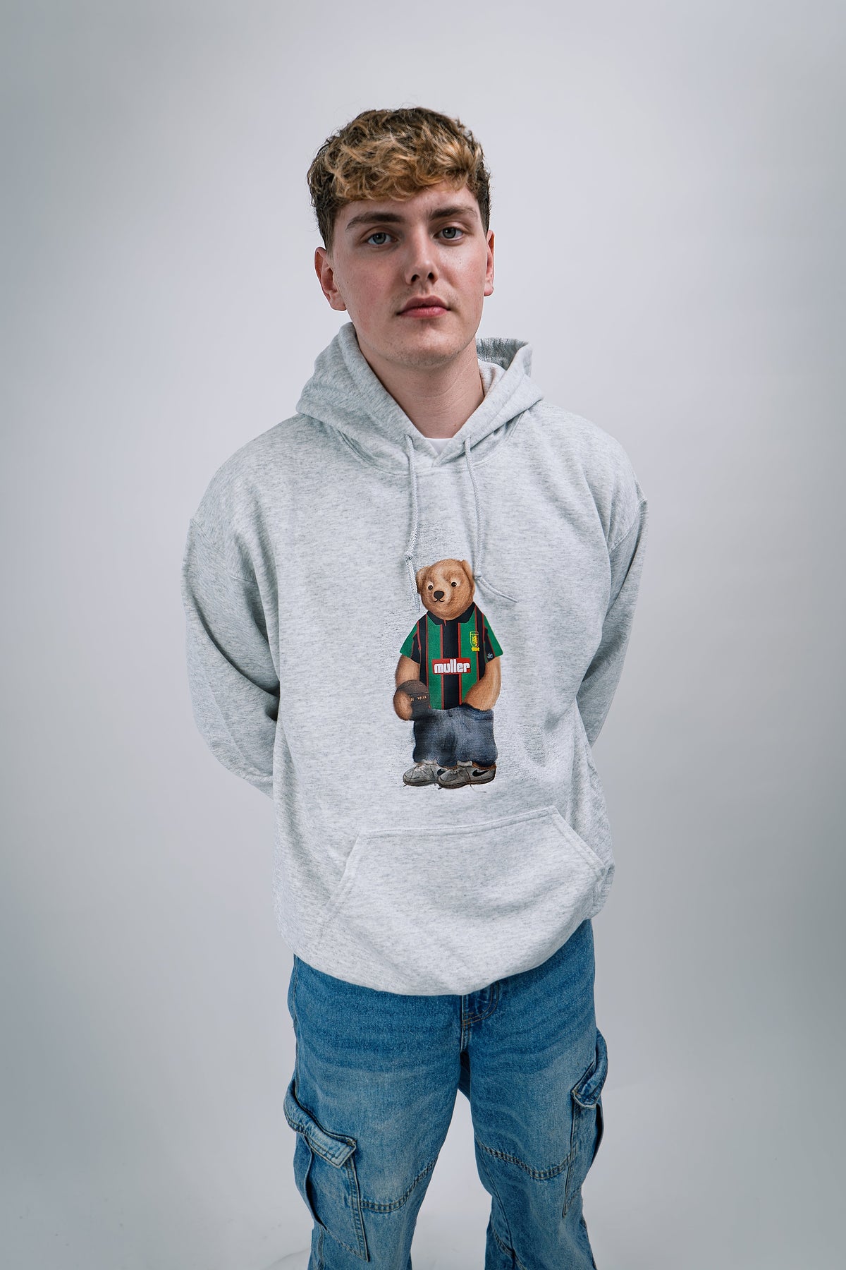 Person wearing a gray hoodie with a bear graphic on a plain background
