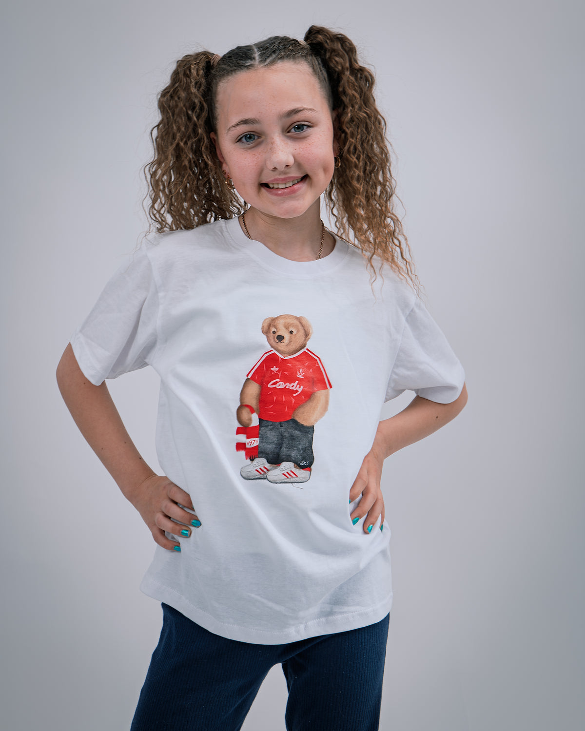 Girl wearing a white t-shirt with a liverpool fc bear graphic and text on a gray background