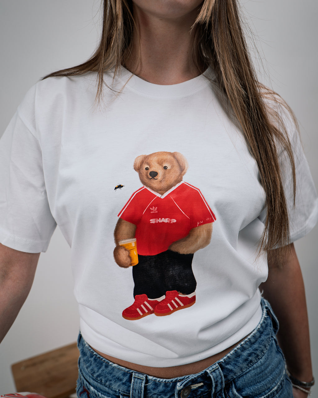 White t-shirt with a bear graphic wearing a red shirt and black pants, holding a beer mug.