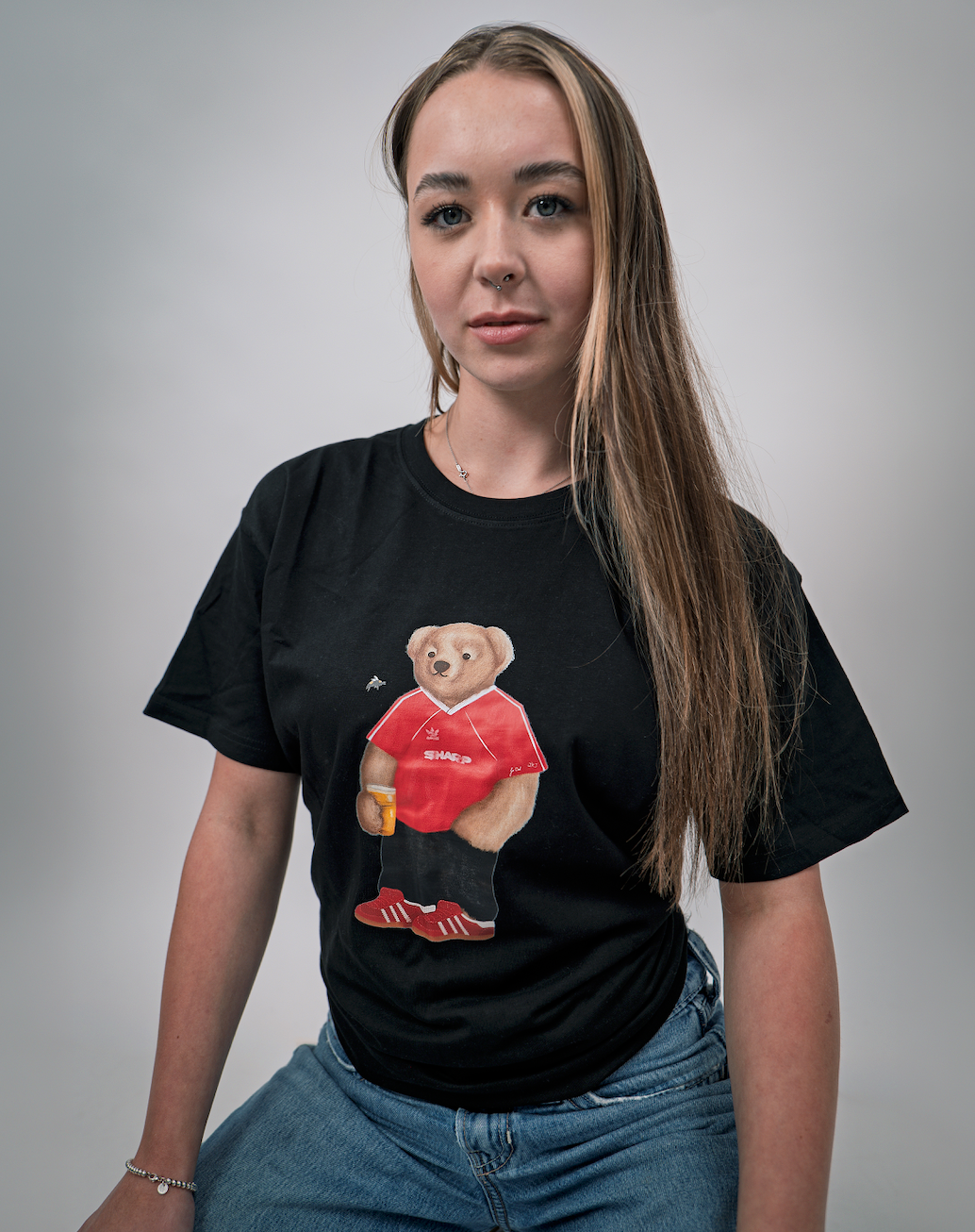 Person wearing a black t-shirt with a bear graphic in a red shirt and red shoes on a gray background