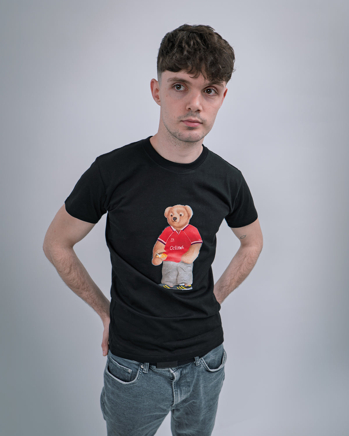 Person wearing a black t-shirt with a graphic of a bear holding a pizza on a plain background