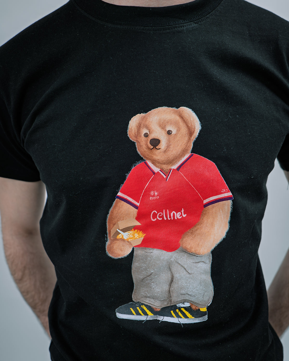 Black t-shirt with a bear wearing a red shirt and holding a bottle, on a plain background.