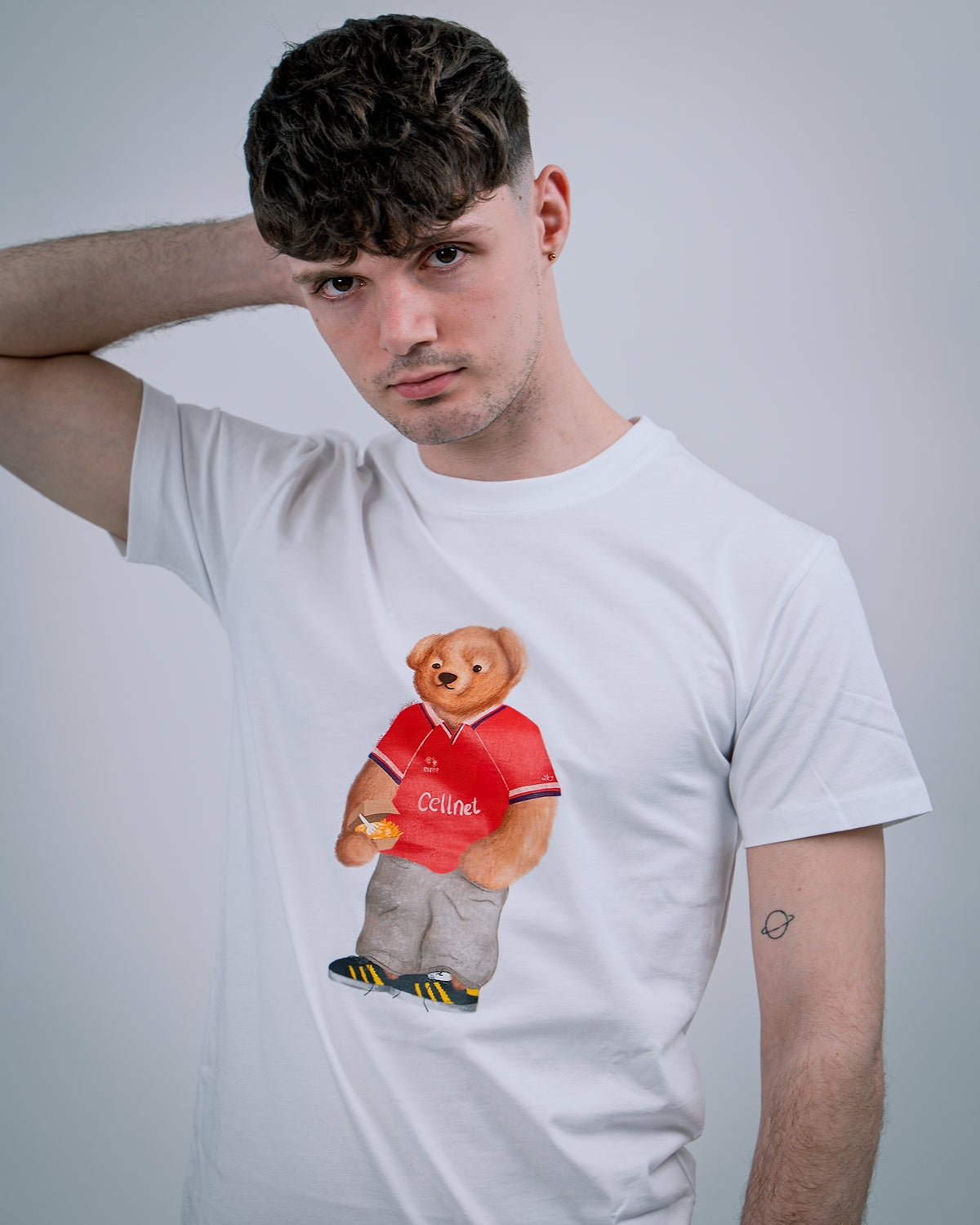 Man wearing a white t-shirt with a teddy bear graphic in the center.