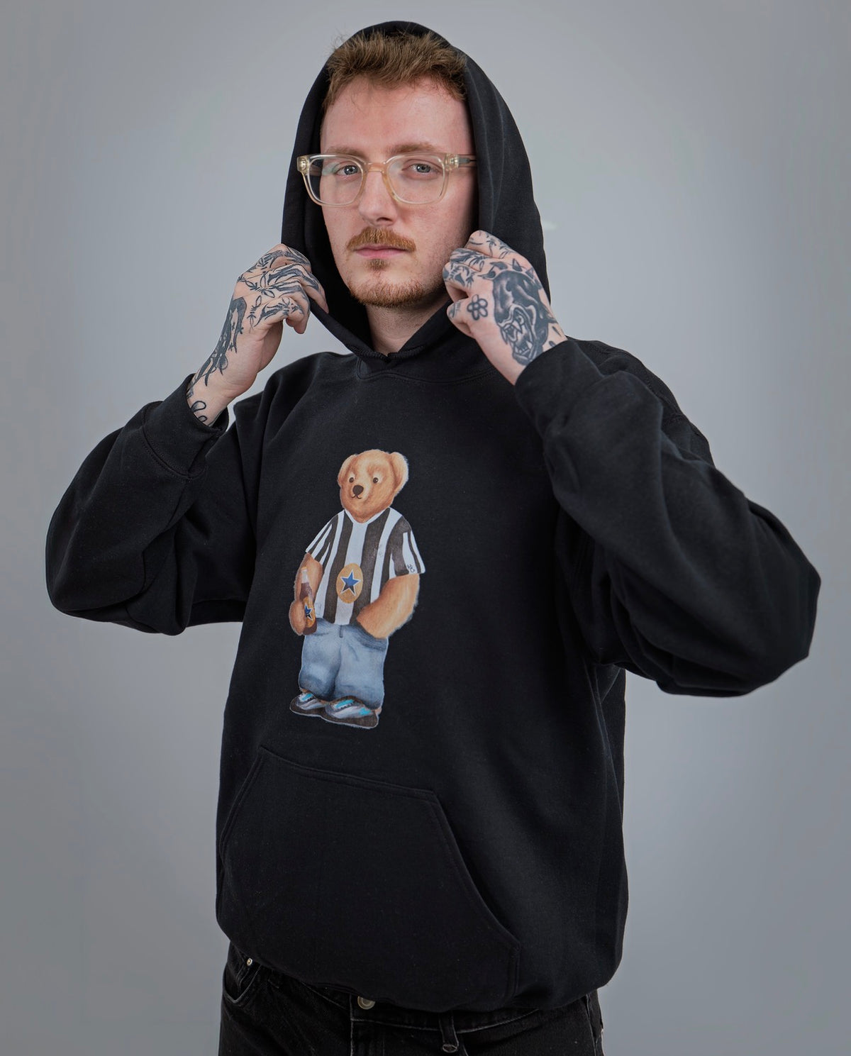 Person wearing a black hoodie with a bear graphic design on a gray background