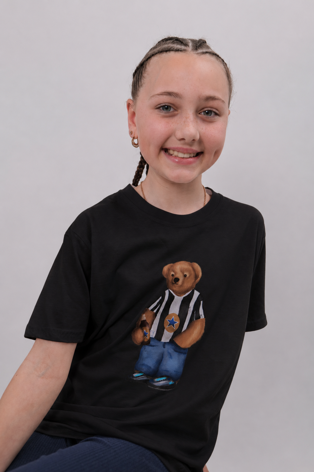 Person wearing a black t-shirt with a teddy bear graphic on a plain background