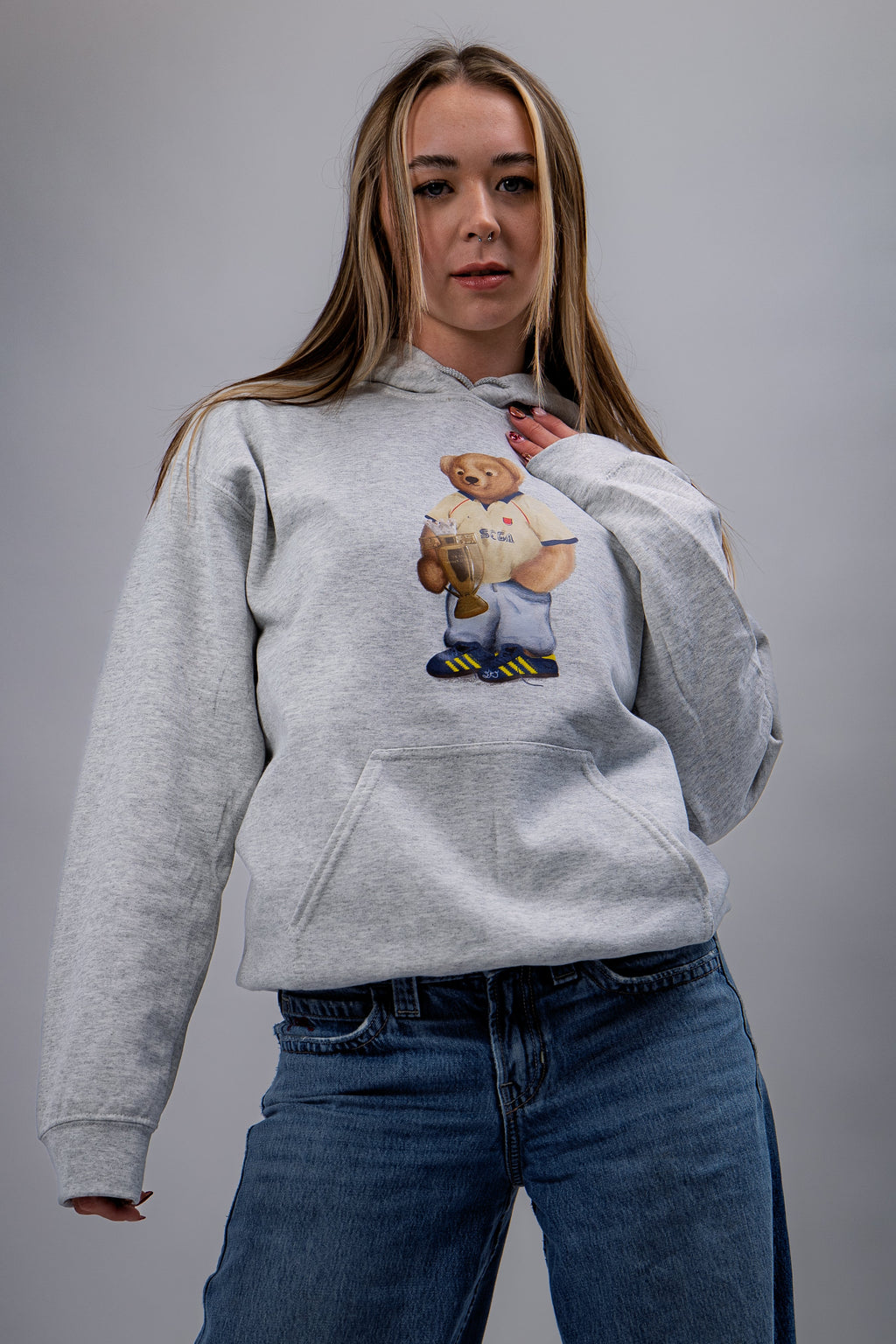 Person wearing a gray hoodie with a bear graphic on a plain background