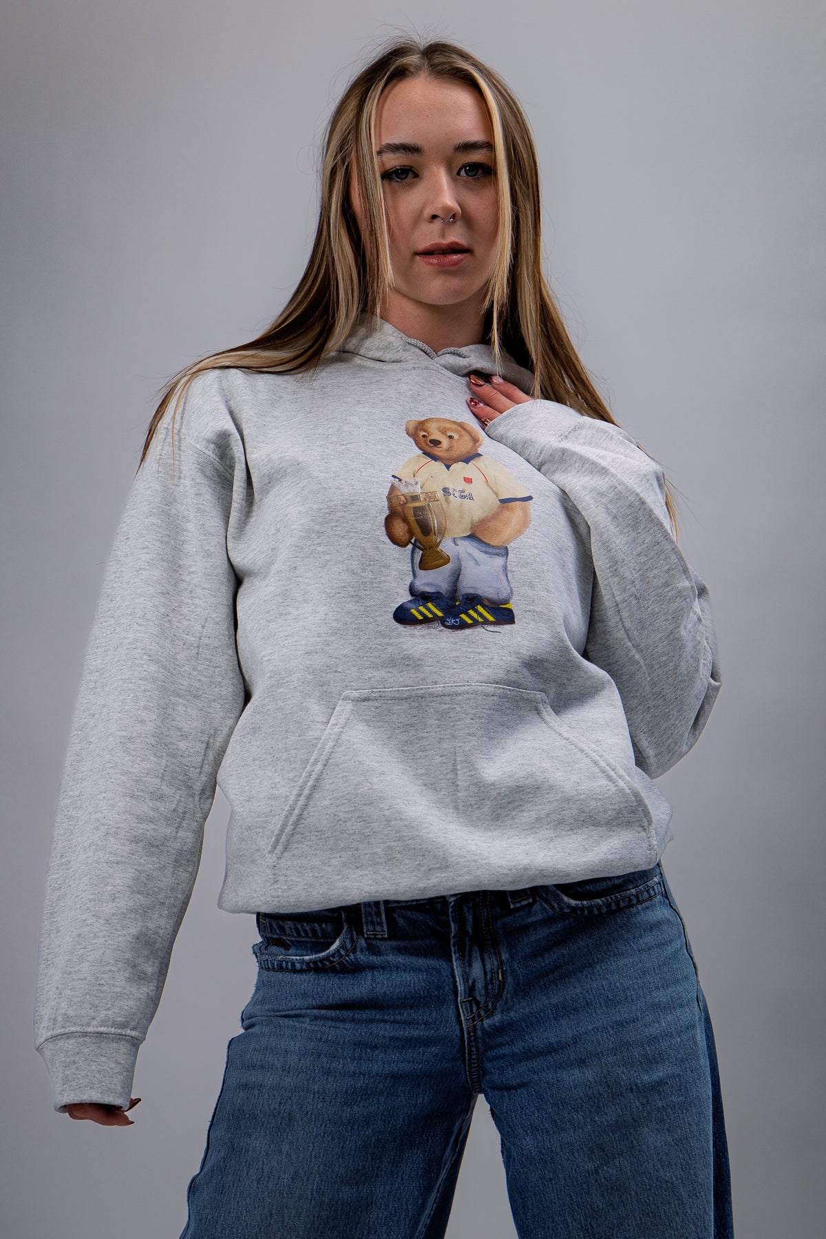 Person wearing a gray hoodie with a bear graphic on a plain background