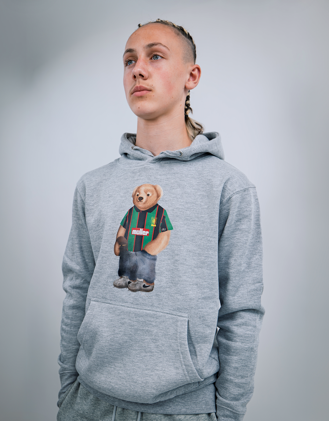 Person wearing a gray hoodie with a bear graphic on a plain background