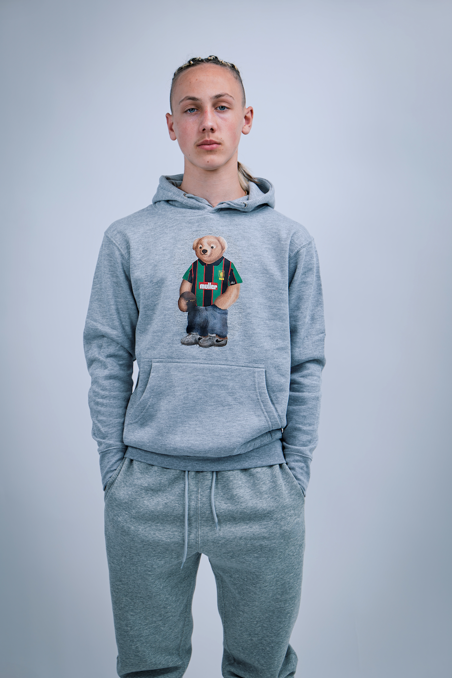 Person wearing a gray hoodie with a teddy bear graphic on a plain background