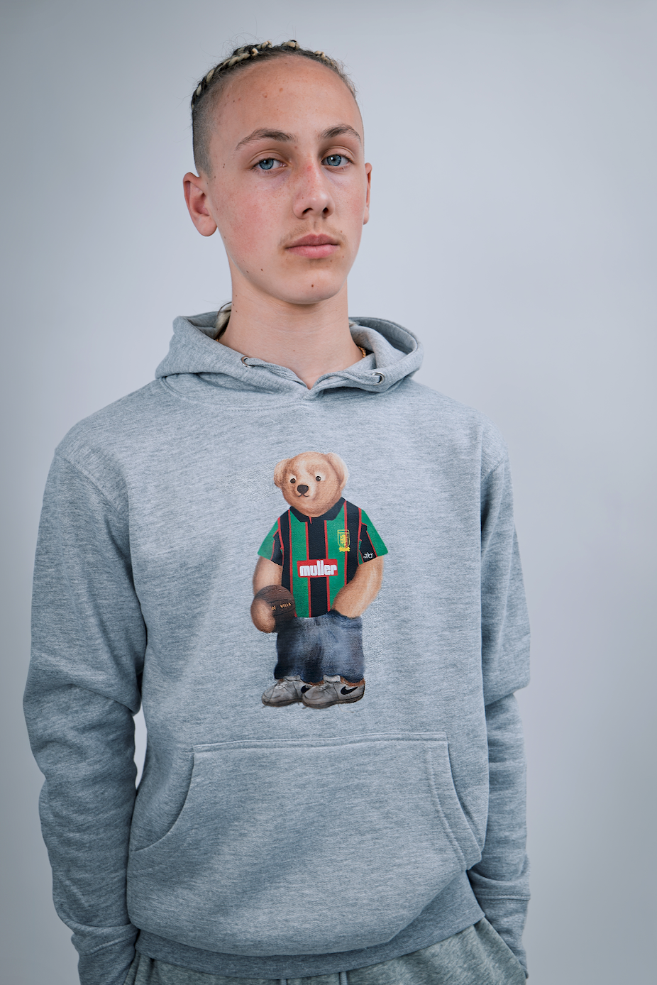 Person wearing a gray hoodie with a bear graphic on a plain background