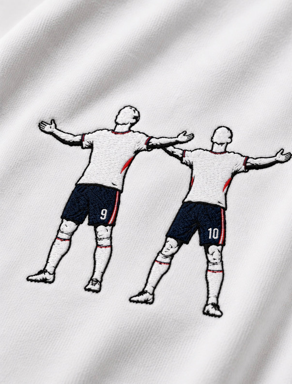 Close-up of a white embroidered tshirt, design is jude bellingham and harry kane celebrating a goal at world cup