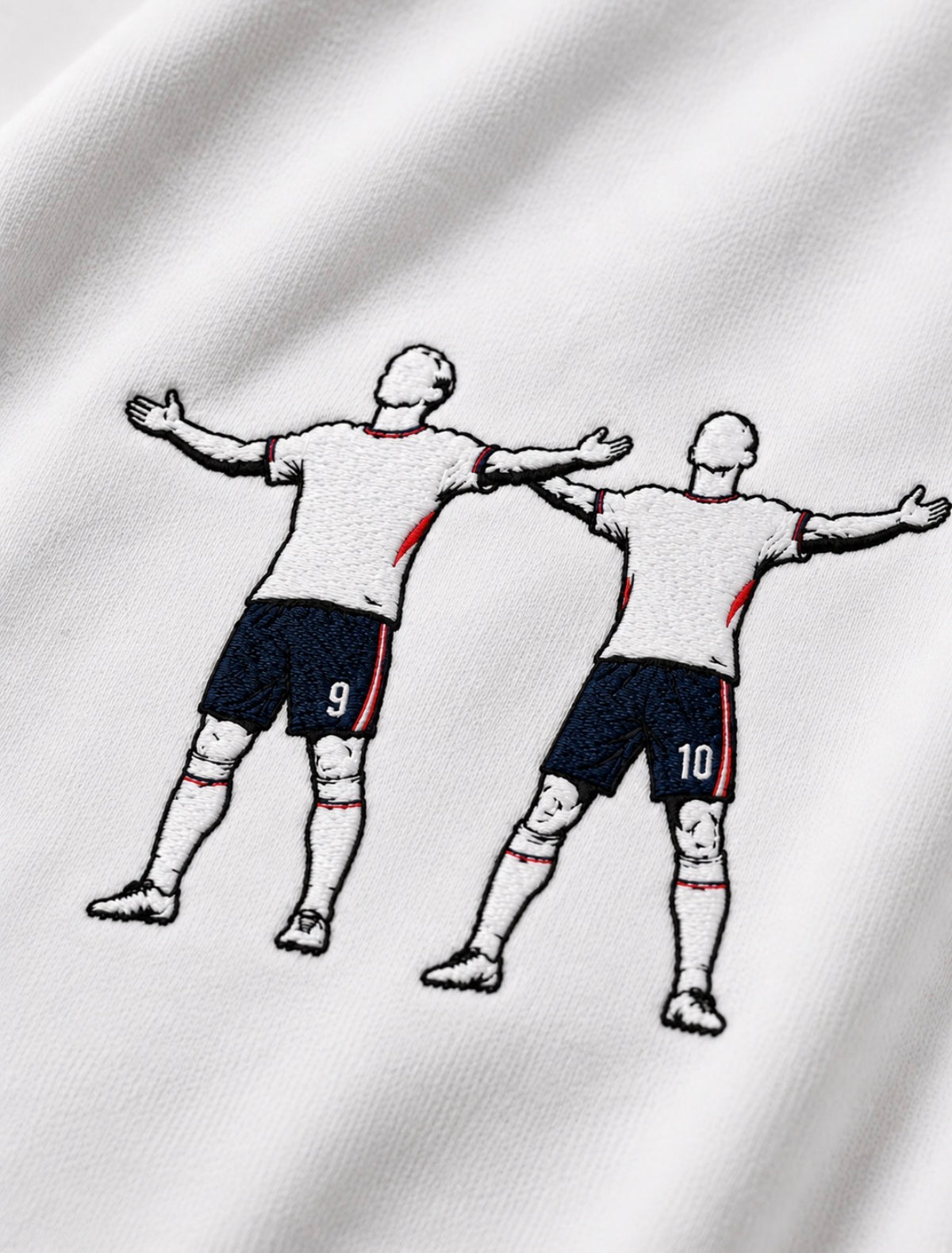 Close-up of a white embroidered tshirt, design is jude bellingham and harry kane celebrating a goal at world cup