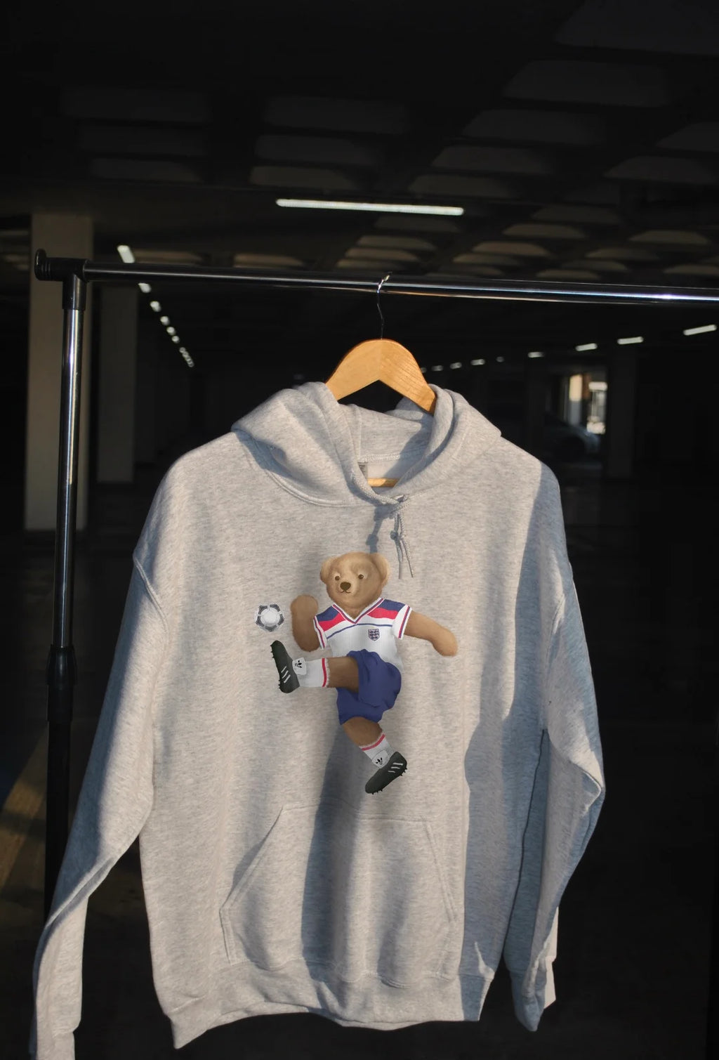 Gray hoodie with a bear graphic on a hanger against a dark background