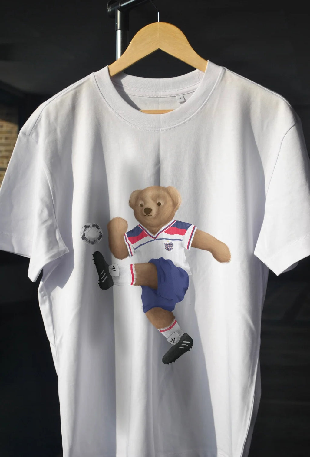 White t-shirt with a bear graphic on a hanger against a black background
