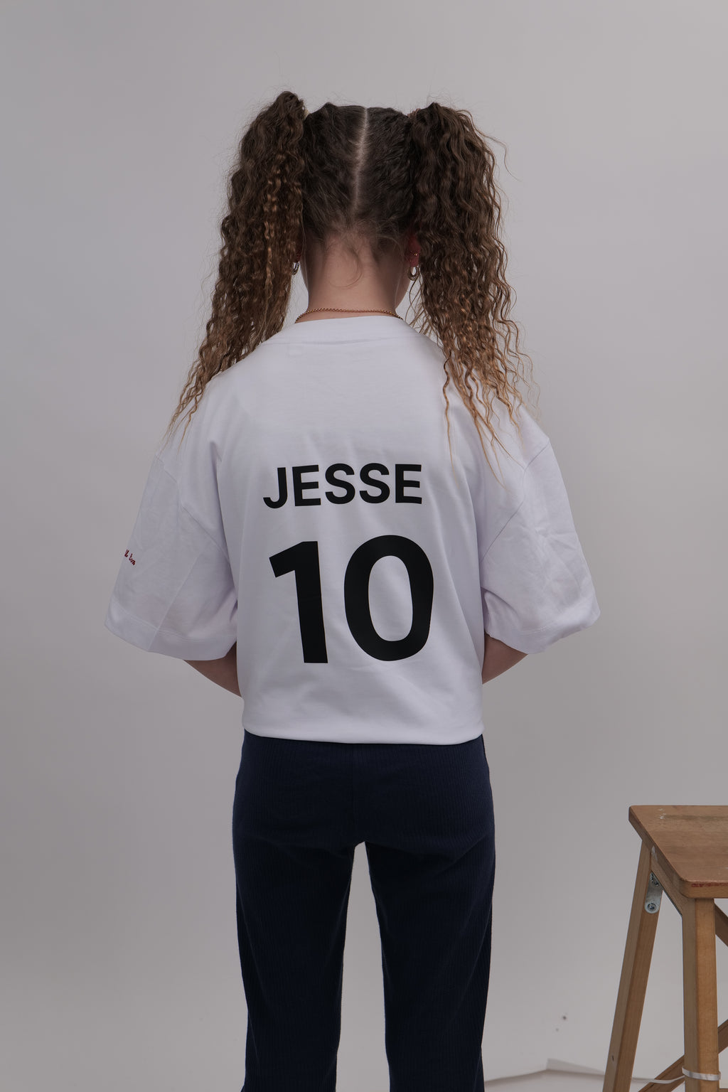 Person wearing a white sports jersey with 'JESSE 10' printed on the back, standing against a plain background.