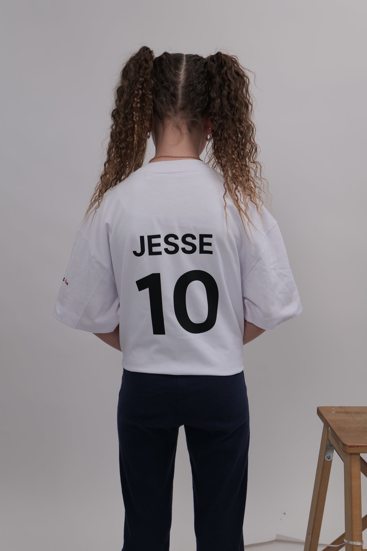 Person wearing a white sports jersey with 'JESSE 10' printed on the back, standing against a plain background.
