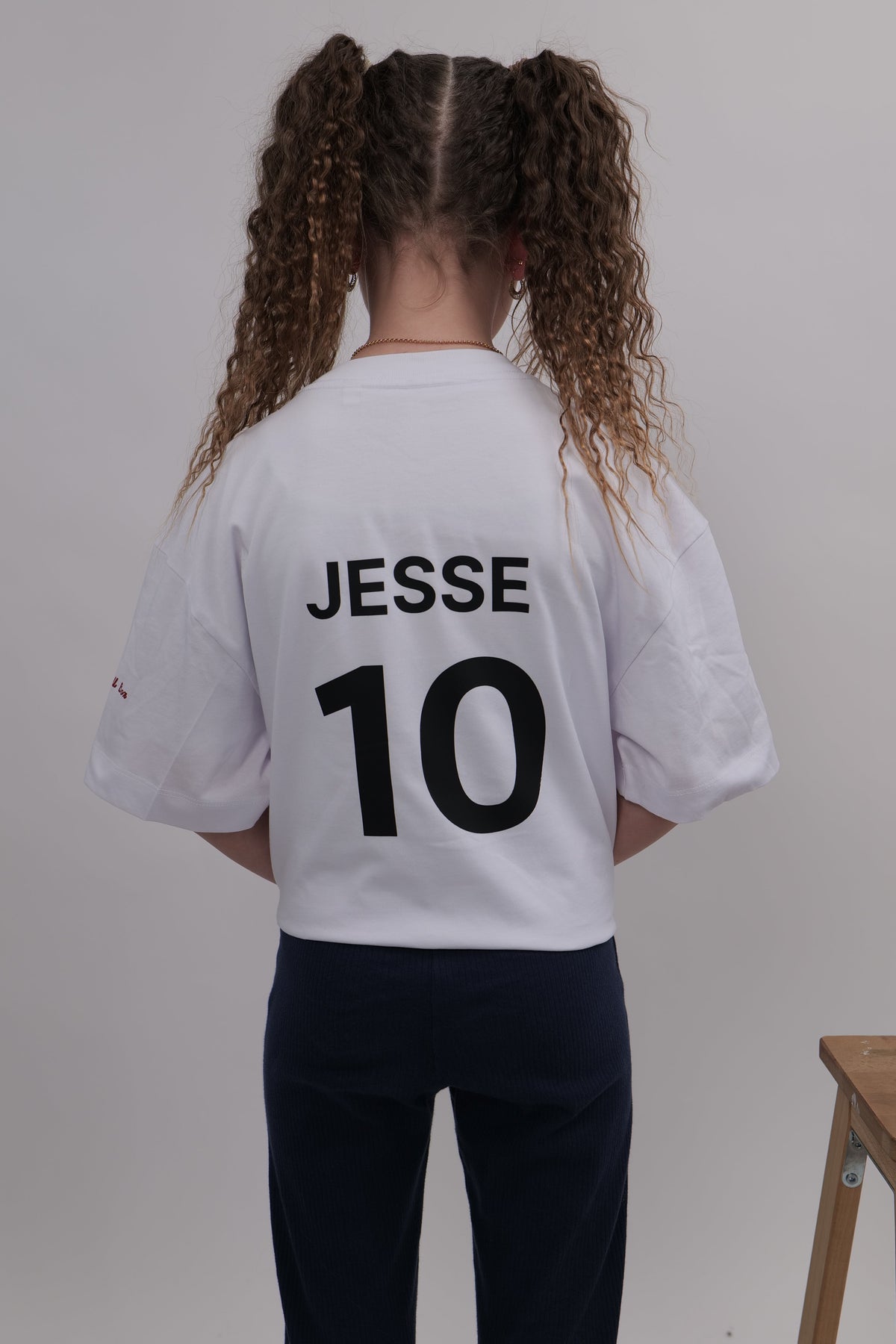 Person wearing a white sports jersey with 'JESSE 10' printed on the back, standing against a plain background.