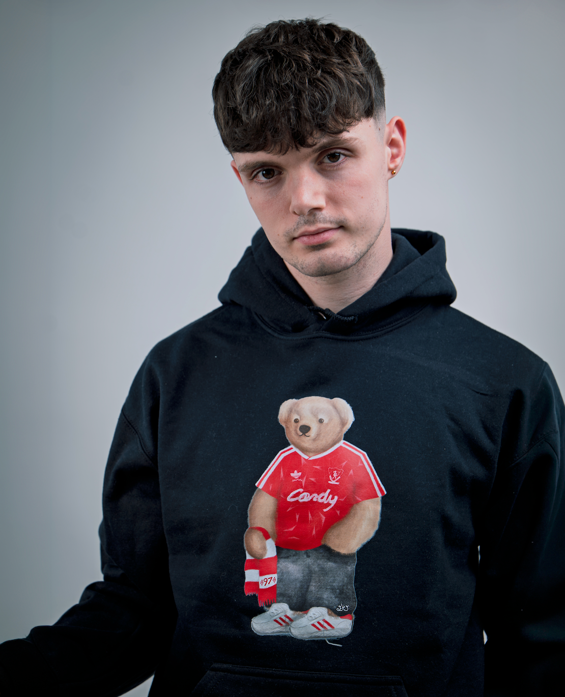 Person wearing a black hoodie with a teddy bear graphic on a gray background
