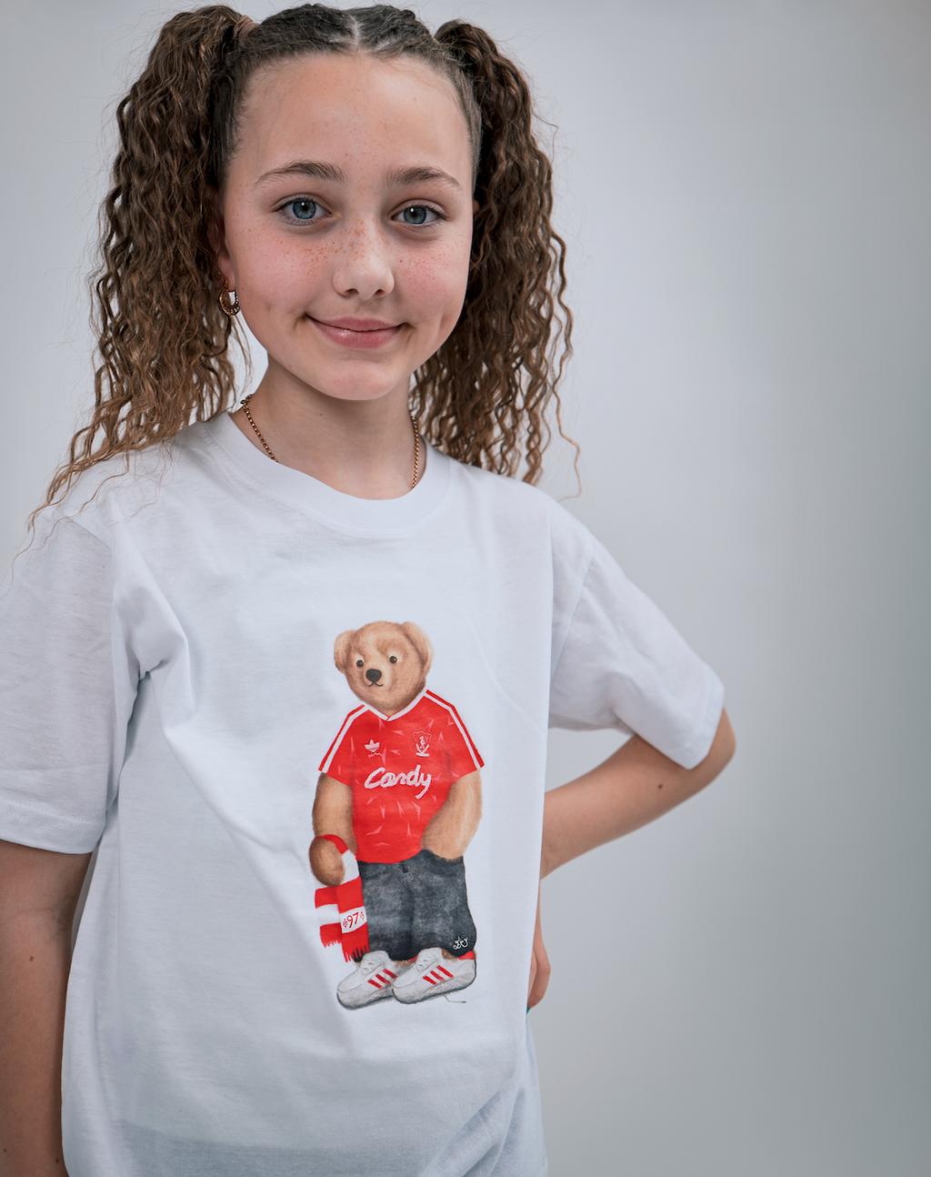 Child wearing a white t-shirt with a bear graphic in a red shirt and shorts.