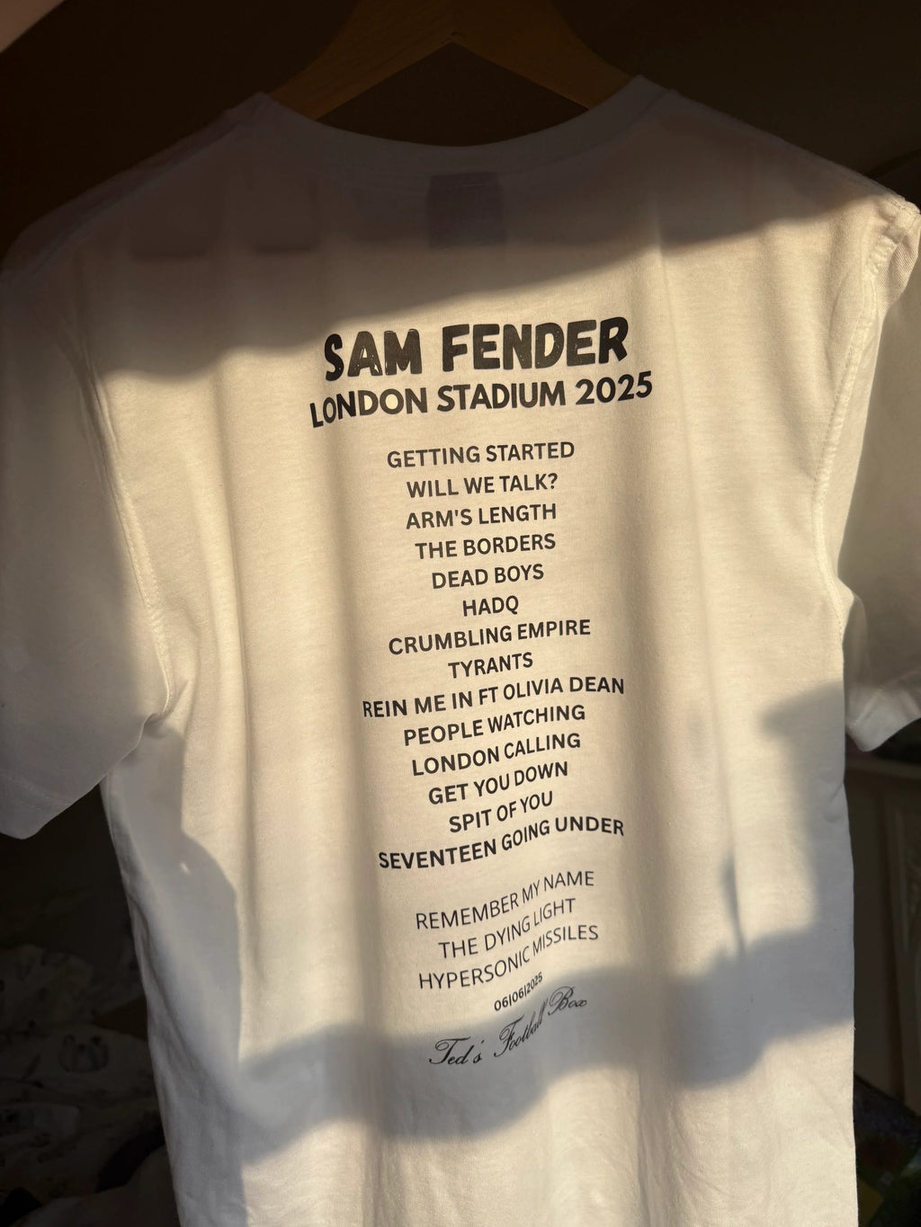 White t-shirt with black text on a hanger