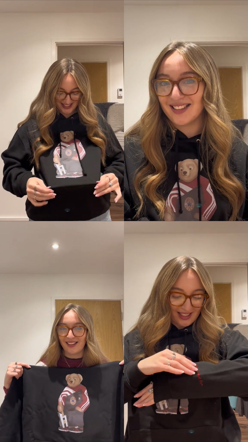 Woman holding a black hoodie with a graphic design, shown from different angles.