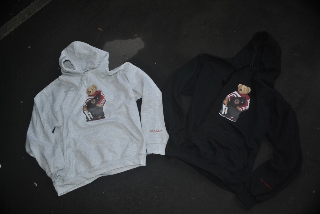 Two hoodies, one gray and one black, with a graphic design on a dark surface.