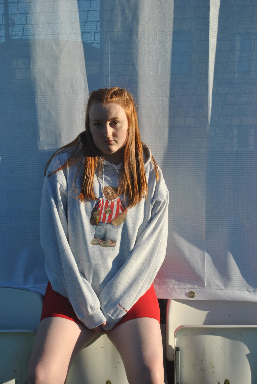 young woman wearing a grey hoodie with a graphic design