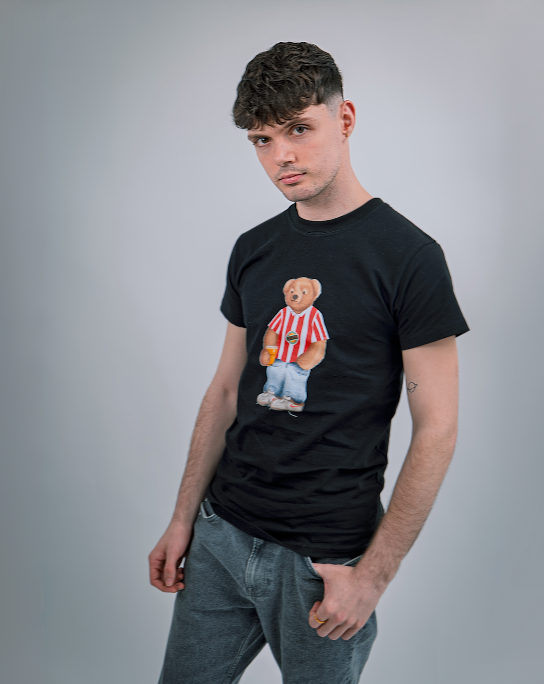Man wearing a black t-shirt with a bear graphic on a gray background