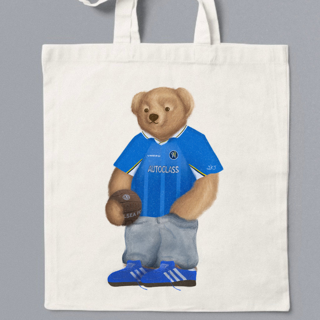 Tote bag with a bear wearing a blue shirt and holding a ball on a gray background