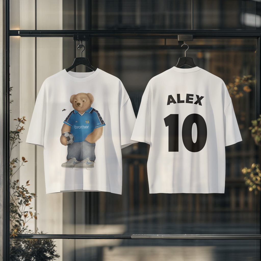 Two white t-shirts with a bear graphic and 'ALEX 10' printed on them, hanging against a blurred indoor background.