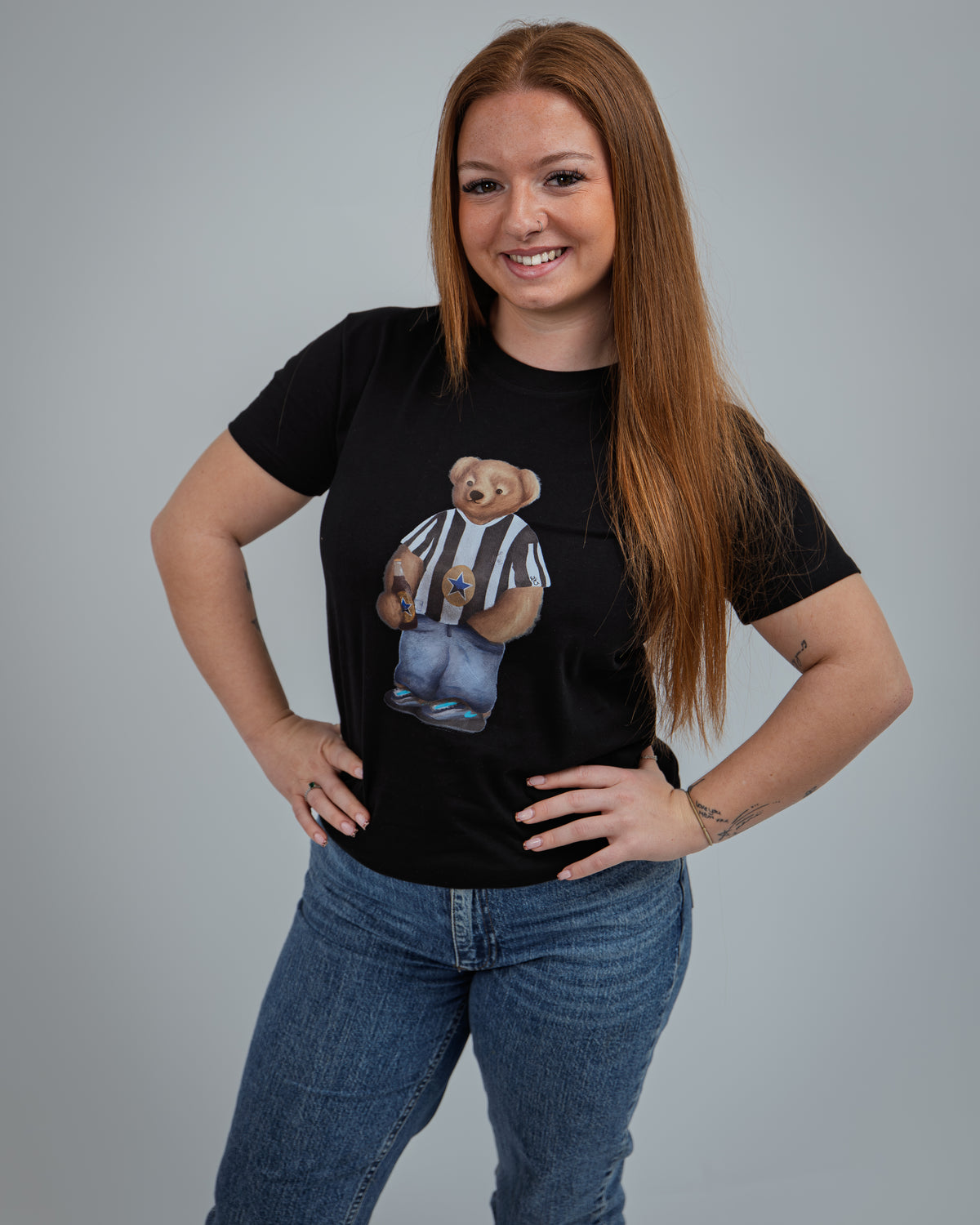Person wearing a black t-shirt with a graphic of two bears in striped shirts and jeans on a gray background